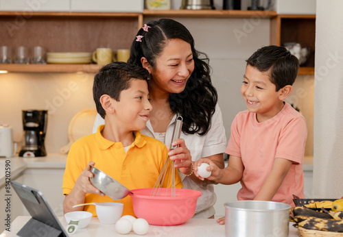 Mom with her Hispanic children preparing a cake at home - family time - happy single mother with her children - Latin lifestyle