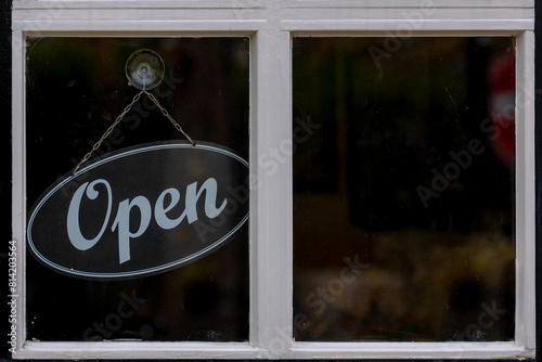 Black wooden sign with word "Open" hanging in front of entrance door, Glass window of Restaurants, Cafe' or Shops, Welcome board for customers or guests, Business and financial background.