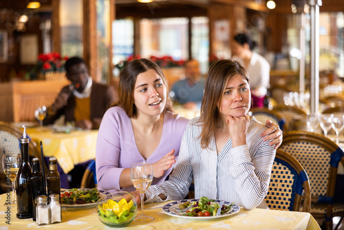 Woman comforting her upset female friend during meeting in restaurant.