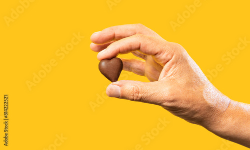 Wallpaper Mural Unrecognizable hand of man isolated on yellow background holding a heart shaped chocolate Torontodigital.ca