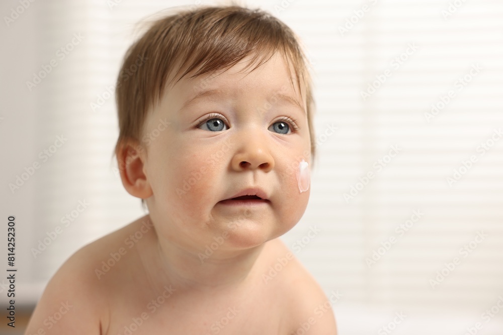 Cute little baby with moisturizing cream on face indoors Cute little baby with moisturizing cream on face indoors