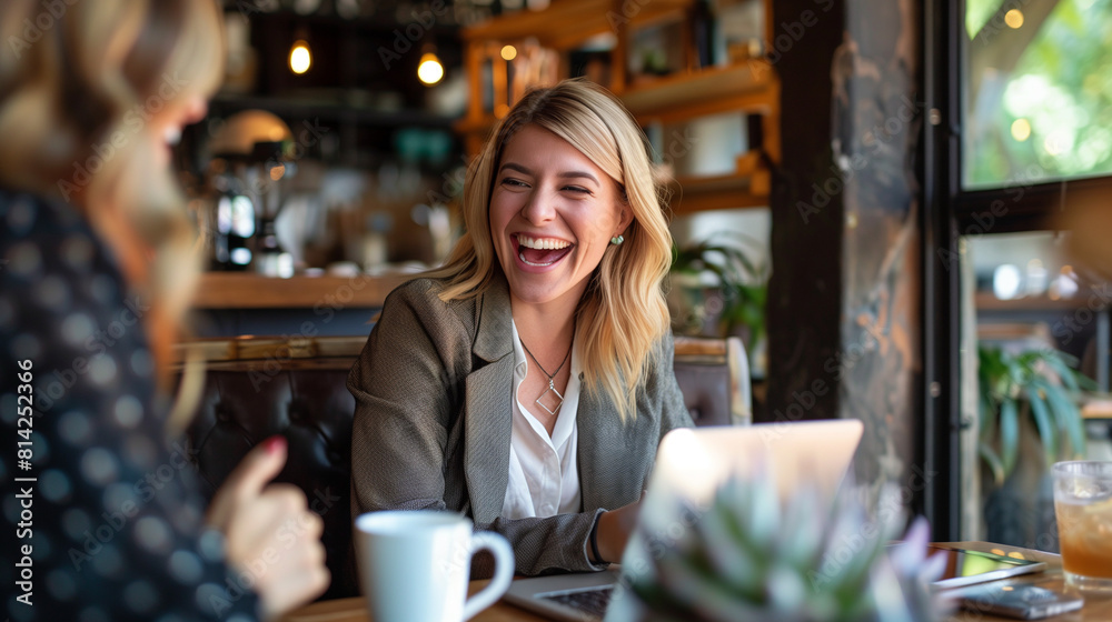 Two Women Laughing at a Table in a Coffee Shop