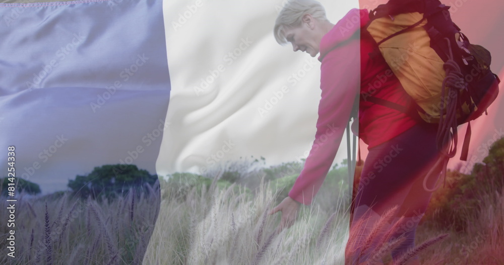 Fototapeta premium Image of flag of france over happy caucasian woman walking at field