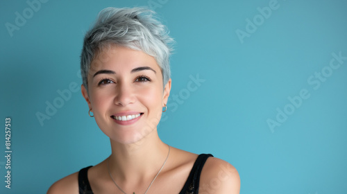 Confident female customer with short, silver hair and a knowing smile, headshot on a serene blue backdrop, radiating quiet confidence.