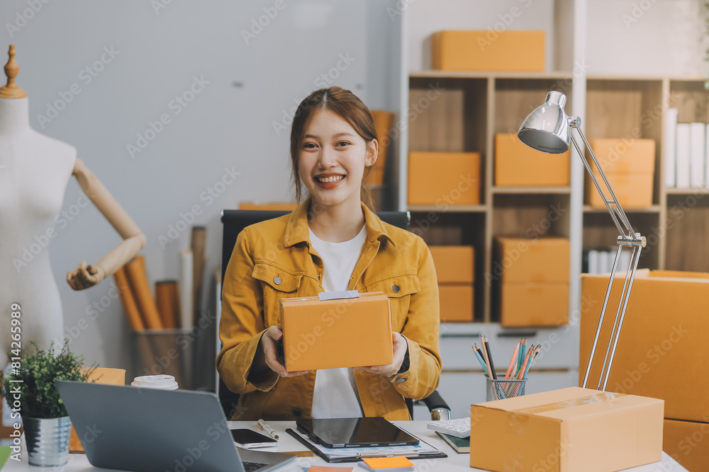 Asian SME business women use laptop computer checking customer order online shipping boxes at home. Starting Small business entrepreneur SME freelance. Online business, Work at home concept. Asian SME business women use laptop computer checking customer order online shipping boxes at home. Starting Small business entrepreneur SME freelance. Online business, Work at home concept.