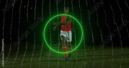 Image of neon geometrical shapes rotating over african american male soccer player