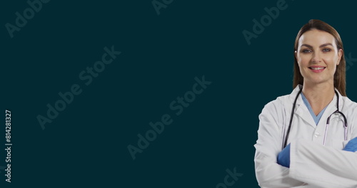 Image of smiling female caucasian doctor standing arms crossed against black background