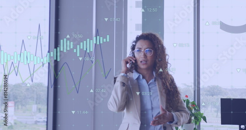 Image of financial data processing over biracial businesswoman talking on smartphone