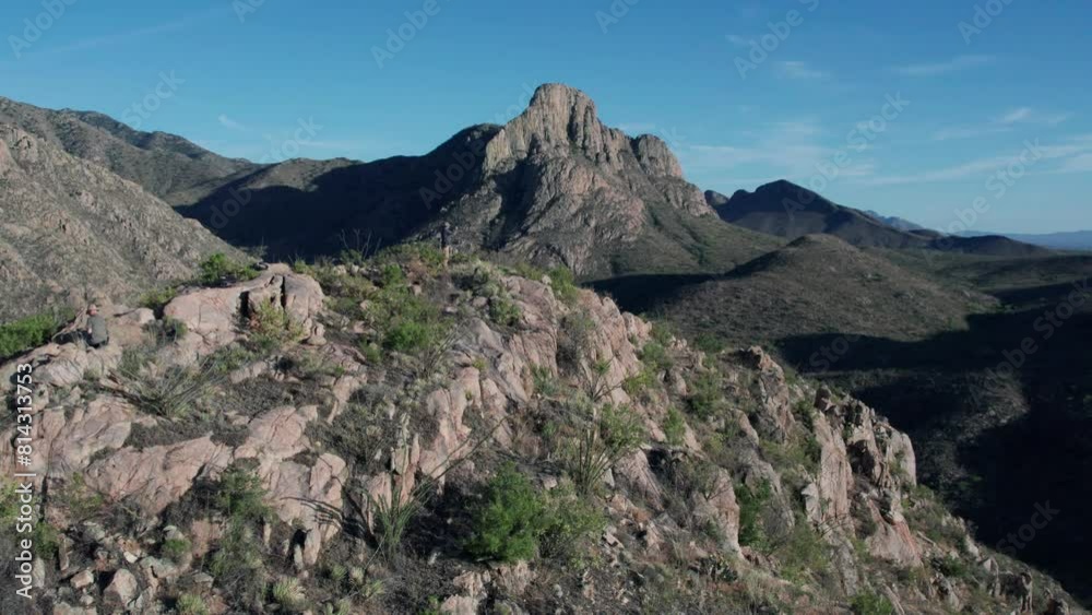 A man at the summit in a dramatic desert mountain range A man at the summit in a dramatic desert mountain range