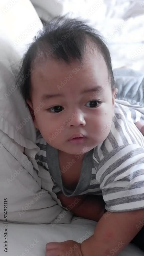 Vertical Format Portrait Video of a Cute Baby Lying face down in Bed. Concept of Childhood, New Life and Parenthood.