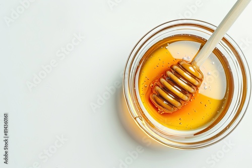 Glass bowl of honey with honey dipper isolated on white background. top view photo