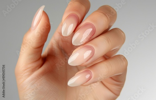 an elegant hand with well-groomed nails  showcasing soft pink nail polish in a perfect oval shape