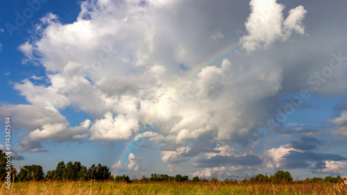 Summer rainbow on a background of white clouds