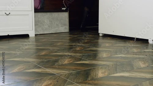 Low section of woman wearing heels walking in room. Closeup of patterned tiles on floor. Interior of house.