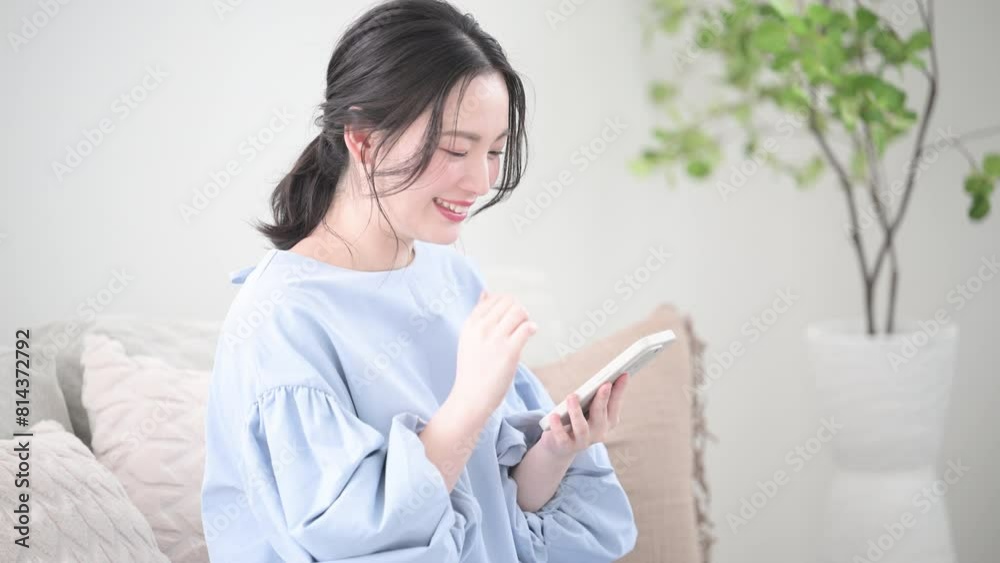 綺麗なリビングでスマホを持ってタップして考える若い女性 画面を見て笑顔で何かを見つけるクローズアップの動画 綺麗なリビングでスマホを持ってタップして考える若い女性 画面を見て笑顔で何かを見つけるクローズアップの動画