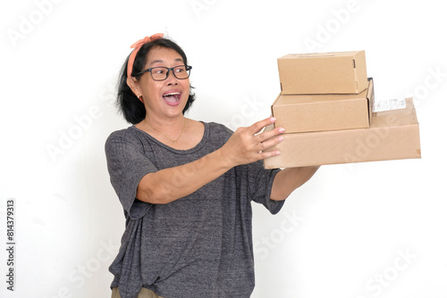 A woman is carrying a stack of boxes; smiling broadly with surprised expression photo