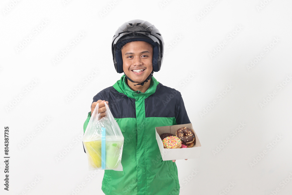 Portrait of Asian online taxi driver wearing green jacket and helmet holding a box of donuts and cup of juice drink, delivering to customer. Isolated image on white background Portrait of Asian online taxi driver wearing green jacket and helmet holding a box of donuts and cup of juice drink, delivering to customer. Isolated image on white background