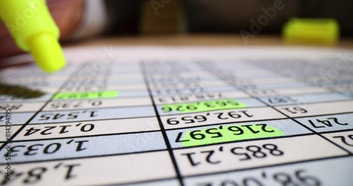 Accountant marks figures in financial report with yellow marker