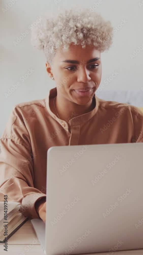 Young happy African American woman puts hands behind head and leans back in chair after finishing work with laptop and paper and successfully completing all tasks from boss sits at desk in office. Young happy African American woman puts hands behind head and leans back in chair after finishing work with laptop and paper and successfully completing all tasks from boss sits at desk in office.