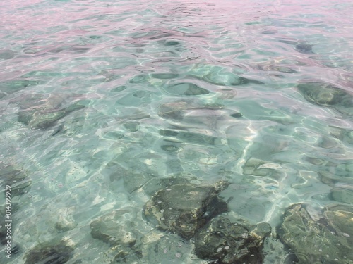 a photography of a body of water with rocks and a boat in the background.