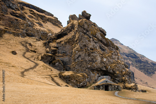 Turf house at foot of Drangurinn Rock in Southern Iceland. Eyjafjll mountains in southern Iceland near Ring Road, Route 1. Turfhouses linked to elves, folklore, sagas, and legends photo