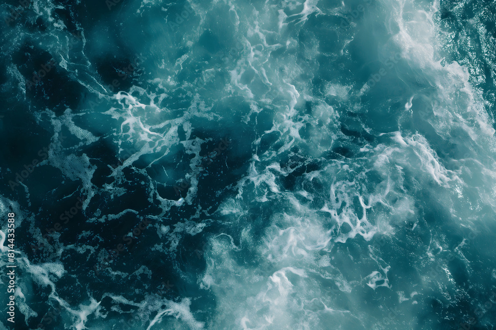 Dynamic photo of the sea's turbulent textures in shades of teal and dark blue, showcasing the chaotic energy of ocean waves