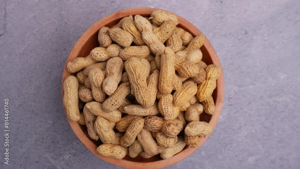 top view of wooden bowl of peanuts spinning on stone table top view of wooden bowl of peanuts spinning on stone table