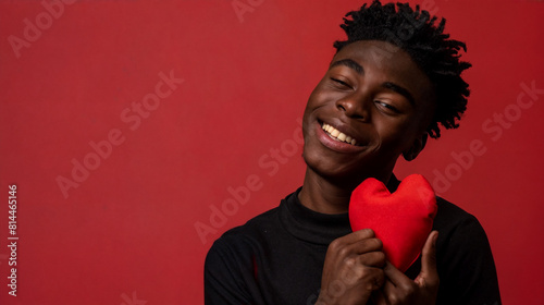 A young romantic man holds a red heart in his hands.