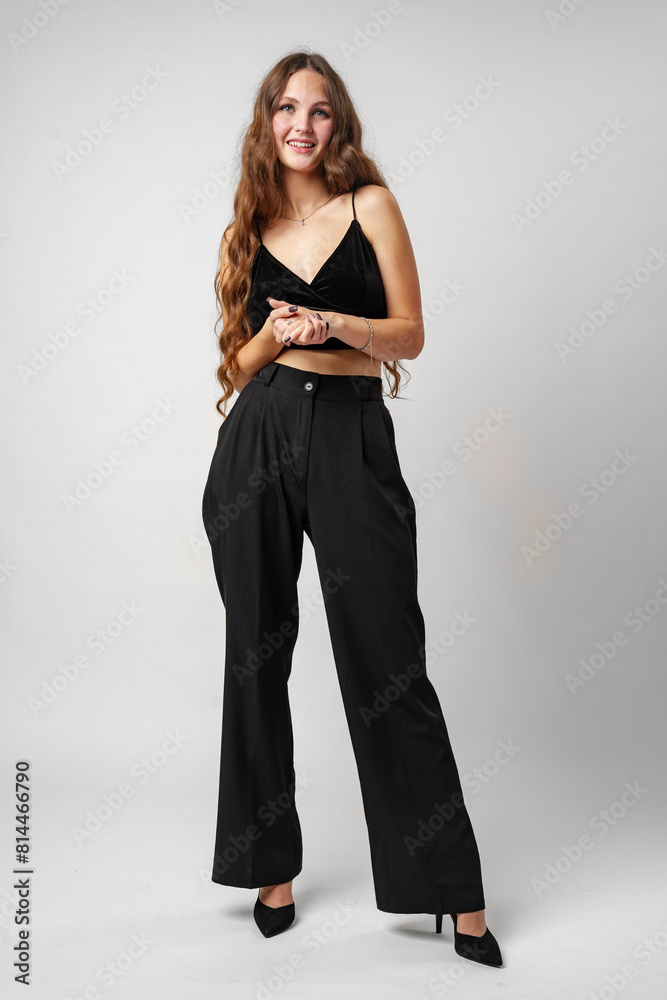 Young Woman in Elegant Black Attire Posing in Studio Against a Neutral Backdrop Young Woman in Elegant Black Attire Posing in Studio Against a Neutral Backdrop