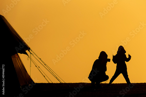 Silhouette, mother photographing baby, yellow background