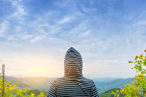The woman wore a hooded shirt, looking at the mountain view at sunset