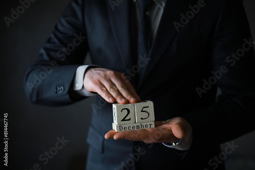 Portrait of businessman ready for Christmas. Wooden cubes with inscription 25 december