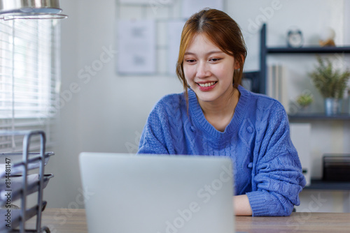 Young asian business woman working at home office with laptop and papers on desk