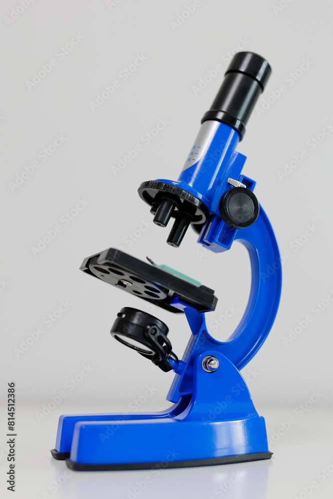 Side view of blue microscope on white table Side view of blue microscope on white table