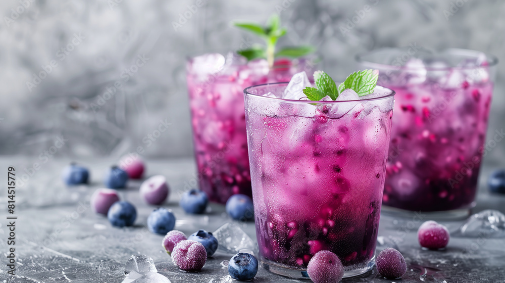 Blueberry purple drink with ice in a glass on gray stone background. A summer refreshing drink Blueberry purple drink with ice in a glass on gray stone background. A summer refreshing drink