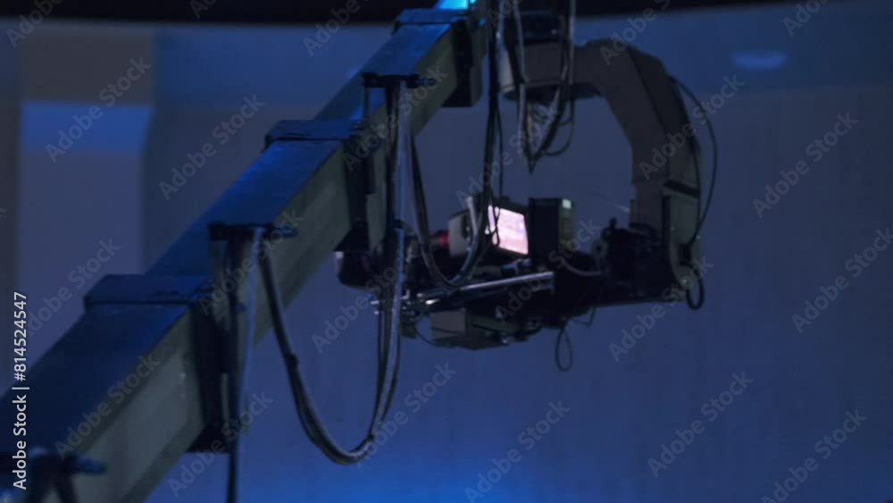 A professional video camera mounted on a crane captures footage in a dark studio environment, highlighting advanced filming technology and expertise in media production. A professional video camera mounted on a crane captures footage in a dark studio environment, highlighting advanced filming technology and expertise in media production.