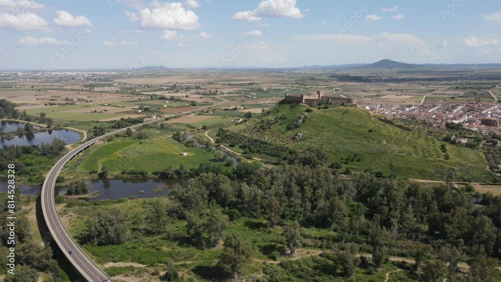 Aerial drone sweeps over Medellín, Badajoz, revealing its ancient castle, meandering river, and picturesque landscape. A timeless vista captured from above.