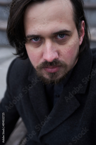 a serious man in a black coat on the street in Krasnoyarsk