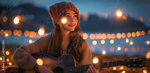 Woman Playing Guitar in Front of String of Lights