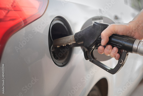 Man refueling the car at a gas station. Close-up of driver hand pumping gasoline car with fuel at the refuel station, higher oil prices