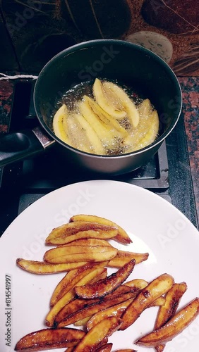 Vertical overhead view of a pot with banana slices being deep-fried beside a plate of fried sugared banana or pritong saging saba, a traditional Filipino merienda food in the Philippines photo