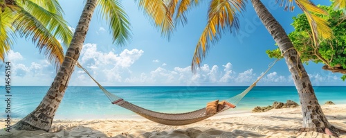 Beautiful tropical beach with a hammock tied between two palm trees, overlooking a clear turquoise ocean under a bright blue sky. The setting exudes relaxation and natural beauty. photo