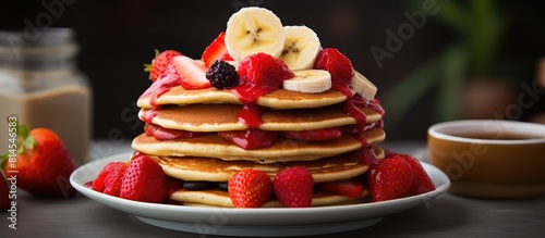 A copy space image featuring crimson hued pancakes garnished with ripe strawberries and sliced bananas photo