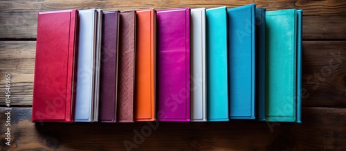 A vibrant assortment of notebooks arranged on a rustic wooden surface providing ample copy space for customization or graphic additions in the image
