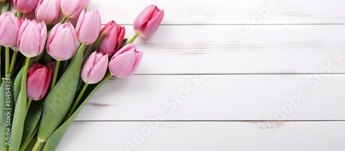 Pink tulips arranged on a white wooden background leaving space for additional images