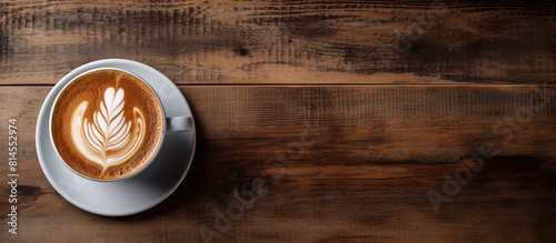 A coffee latte with a beautiful latte art design placed on top set on a rustic wooden table creating an appealing copy space image