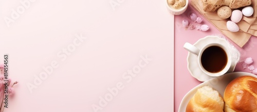 A pink background displays a blank notepad adorned with a sweet bun Easter decorations and baking tools in a photograph with ample copy space