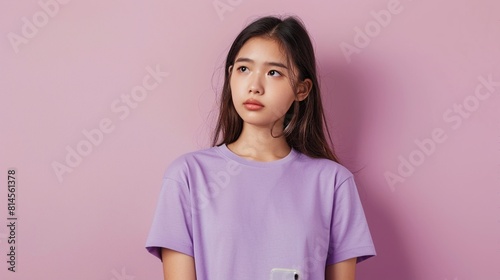 young asian woman in purple t-shirt is thinking something and confused on pink background.