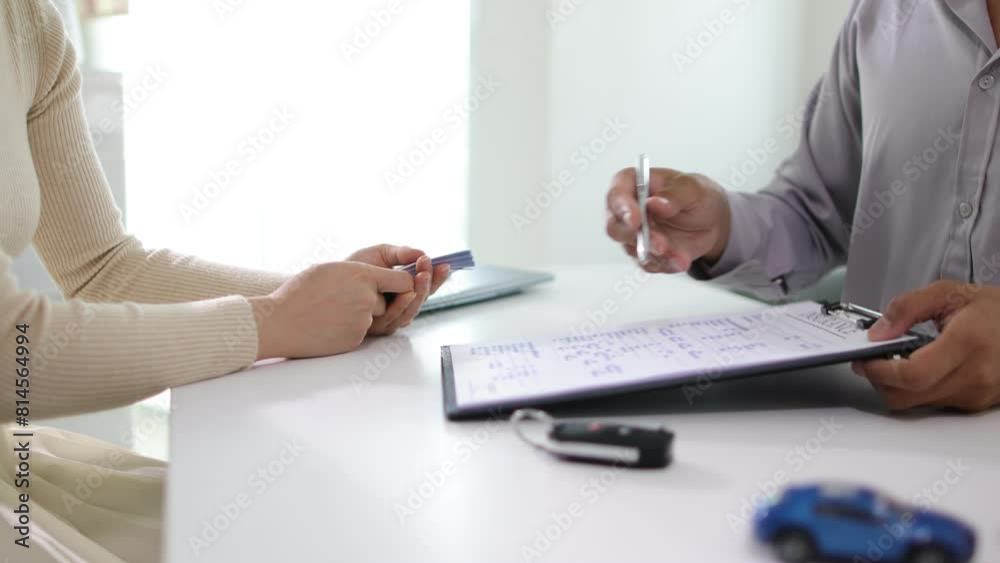 Woman signs a car purchase and insurance contract with a dealer, she pays money and receives the car keys.