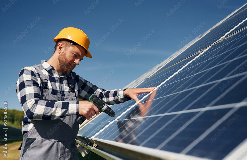 Almost done, installation by using drill. Engineer with photovoltaic solar panels outdoors at daytime Almost done, installation by using drill. Engineer with photovoltaic solar panels outdoors at daytime